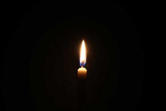 Dark candle light, one light of yellow candle on black background.