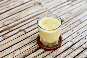 Banana smoothie in the glass on the old wooden background