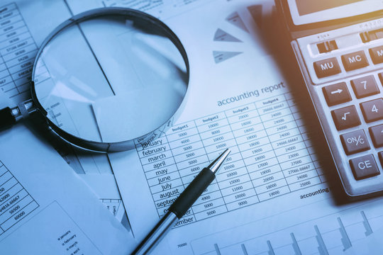 finance accounting concept. pen and calculator with magnifying glass on table