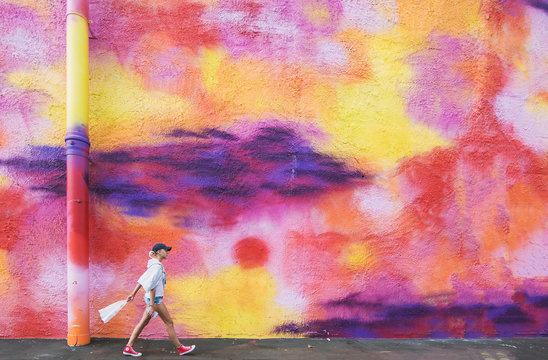 Frau läuft vor bunter Wand in Auckland