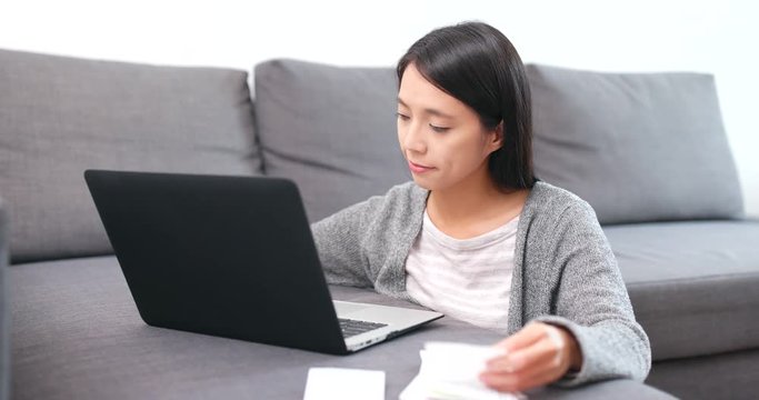 Woman using laptop computer for recording the expense of the receipt