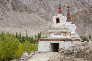 Buddhist chortens, white stupa and Himalayas mountains in the background near Leh in Ladakh, India