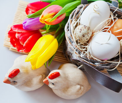 Czech traditional easter decoration - white eggs in a basket, wooden chichen and tupil flowers