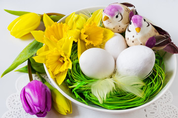Czech traditional easter decoration, white eggs  in the nest with flowers and two birds - tulipas nad daffodil