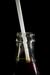 The neck of a cola bottle with a straw