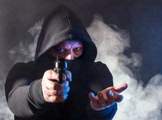 ein maskierter Mann macht bei Dunkelheit einen bewaffneten Überfall
