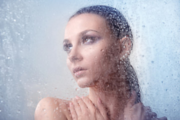 Glamorous brunette woman with makeup smoky eyes with water drops and close-up in profile on a light background