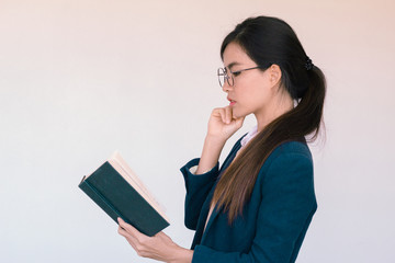 Young Asian businesswoman wearing blue suit and holding a book  and reading