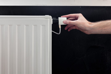 Radiator adjustment closeup. Man's hand adjusting radiator temperature.