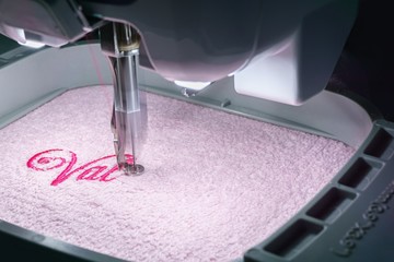 Embroidery machine embroidering on pink towel in the hoop Close up image