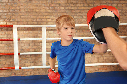 Little boy with trainer on boxing ring