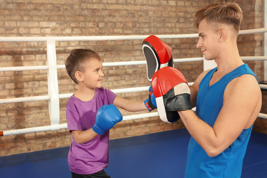 Little boy with trainer on boxing ring