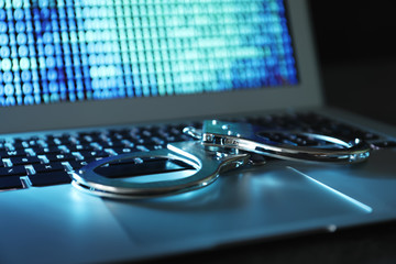 Handcuffs on laptop keyboard, closeup