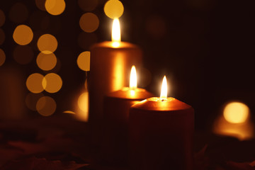 Beautiful burning candles in darkness against defocused lights