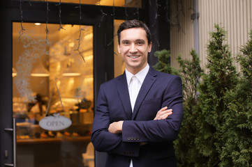 Young man standing near store. Small business owner portrait