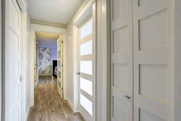 Long, narrow corridor with white doors accented with glass panels