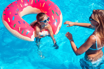 Little girl with her mom in swimming pool.