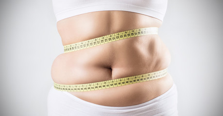 Overweight woman measuring her fat belly.