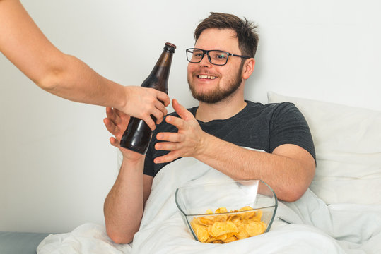 man lay in the bed hand give him a beer