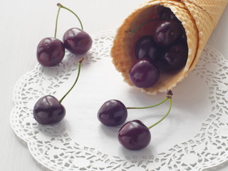 Close up image of fresh cherries in a wafer cornet lying upon white napkin. Selective focus.