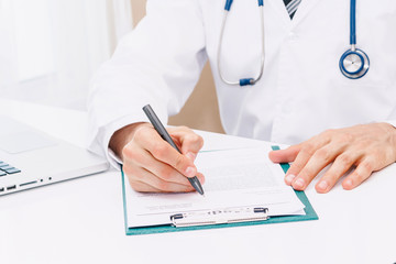 Fototapeta premium Doctor with stethoscope working and writing on paperwork in hospital.healthcare and medicine