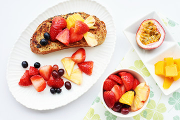 Top view of sweet french toast with fresh fruits and berries: strawberry, grape, mango, passion fruit, pineapple. Healthy breakfast.
