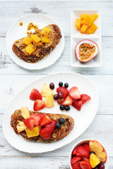 Top view of sweet french toasts with fresh fruits and berries: strawberry, grape, mango, passion...