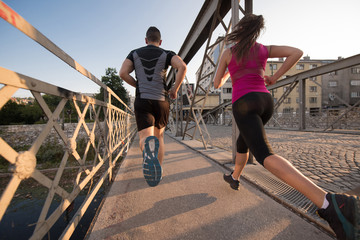 Fototapeta na wymiar young couple jogging across the bridge in the city