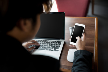 close up Business man holding big smart phone and use laptop computer