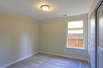 Empty room interior with beige walls and wall to wall carpet.