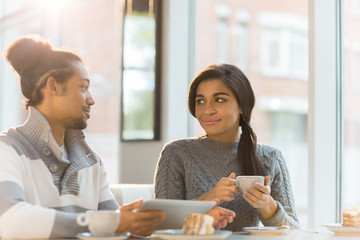 Young Hispanic or multi-cultural couple sitting in cafe at leisure and relaxing