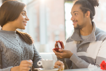Surprised girl looking at her boyfriend with open ring-box with engagement ring inside