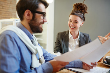 Obraz premium Happy female economist or banker and her colleague discussing papers or contracts