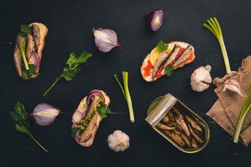 A set of sandwiches with sprats, and caviar, onion and parsley, on a wooden background. Top view. Copy space.