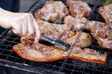 Hand of young woman grilling some meat