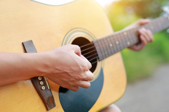 Close-up male hands playing on acoustic guitar in the nature.