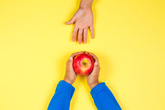 Kid Hand Taking Red Apple From Another Child's Hands