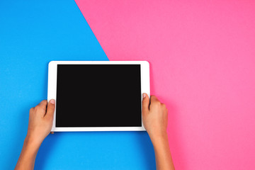 Kid hands with tablet computer on pink background.