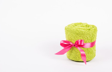 Roll of green terry towel. Soft towel with bow on white background