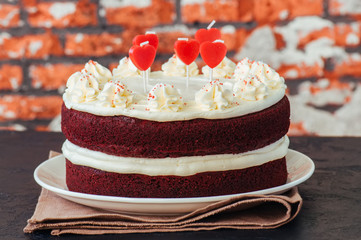 Red velvet cake with cream cheese frosting on a white plate