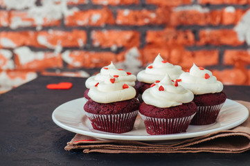 Red velvet cupcakes with cream cheese frosting on a white plate