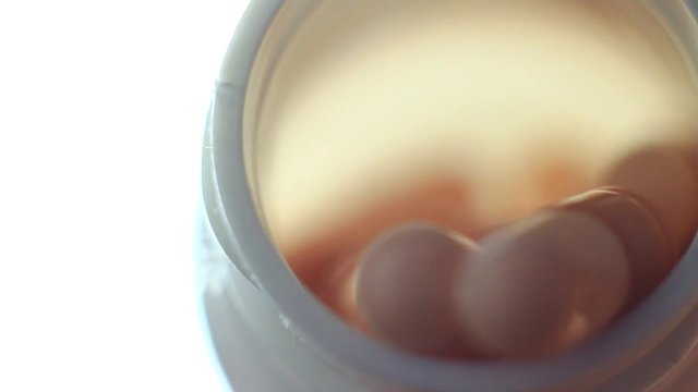Pills in a plastic containet. Close up. Macro. Soft light from back.