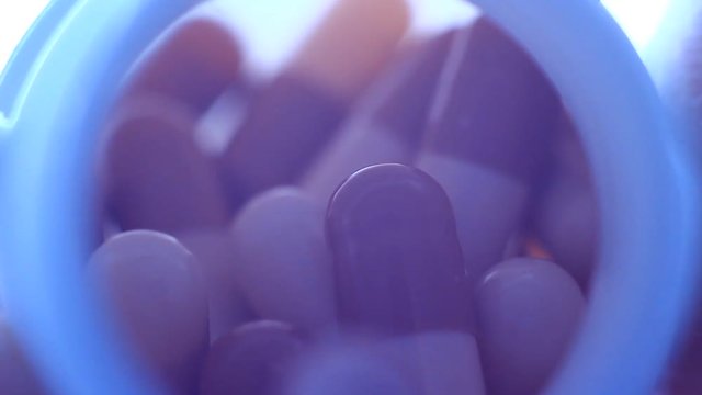 Pills in a plastic containet. Close up. Macro. Soft light from back.