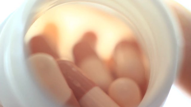 Pills in a plastic containet. Close up. Macro. Soft light from back.