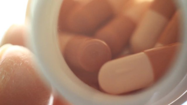 Pills in a plastic containet. Close up. Macro. Soft light from back.