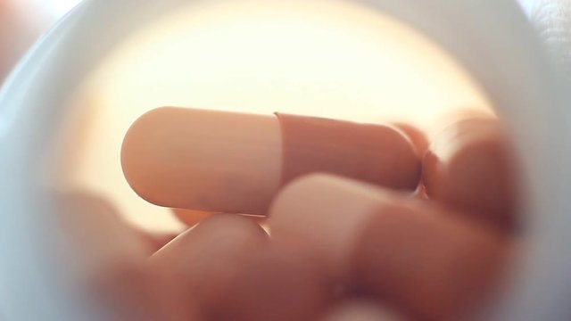 Pills in a plastic containet. Close up. Macro. Soft light from back.