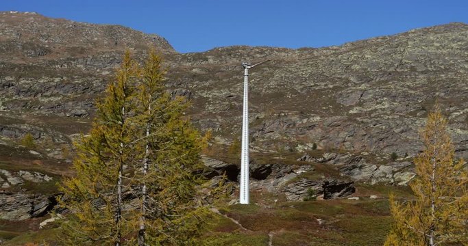 Wind power generator, Slow motion handheld view of a wind machine, spinning around, in a alpine valley, on the top of simplon pass, on a sunny autumn day, in Valais, Switzerland