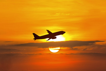 Airplane fly on sunset sky.