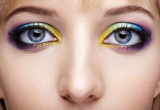 Closeup macro image of human female eye with violet, blue and and yellow makeup
