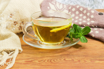 Tea with lemon and mint beside of woolen mittens, scarf